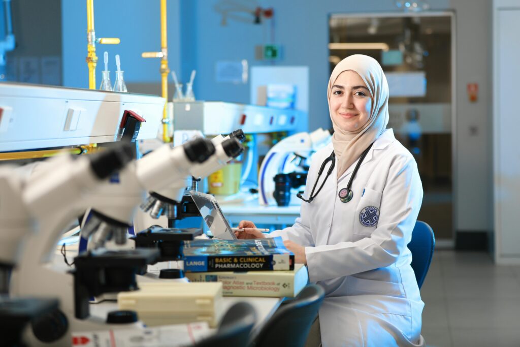 A female scientist in a laboratory setting, conducting research with microscopes and reference books.